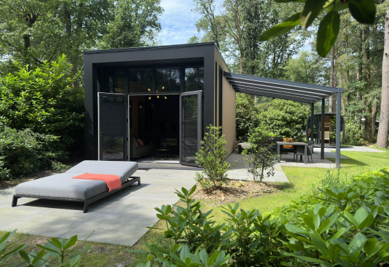 Moderne Veluwe Suite lodge met sauna, terras en ligbed, omgeven door groen en bossen in de natuur.