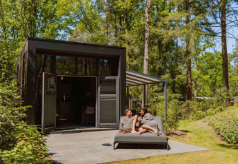 Coppia si rilassa fuori dalla Veluwe Suite con sauna al Camping Samoza, circondata da boschi nei Paesi Bassi.