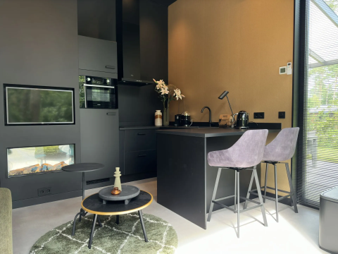 Moderne compacte lodgekeuken met zwart interieur, ontbijtbar en haard in Veluwe Suite met sauna, Samoza.
