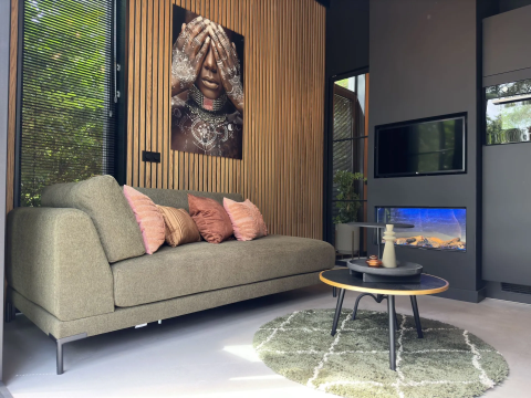 Modernes Wohnzimmer in der Veluwe Suite mit grüner Couch und stilvoller Dekoration auf Camping Samoza.