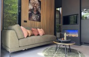 Eigentijdse living in de Veluwe Suite met groene zetel en wandkunst bij Camping Samoza, Nederland.