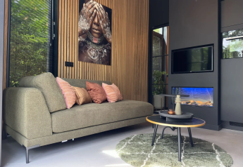 Interno moderno della Veluwe Suite con divano verde, arte murale e decorazioni a Camping Samoza nei Paesi Bassi.