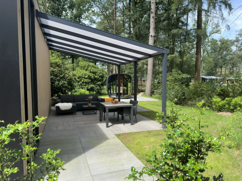Moderne Terrasse mit Überdachung und Gartenmöbeln im Veluwe Suite mit Sauna auf Camping Samoza in den Niederlanden.