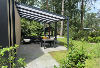 Moderne Terrasse mit Überdachung und Gartenmöbeln im Veluwe Suite mit Sauna auf Camping Samoza in den Niederlanden.