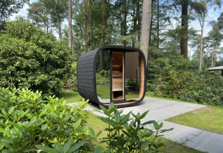 Moderne buitensauna bij Veluwe Suite op Camping Samoza in Nederland omringd door groene natuur.