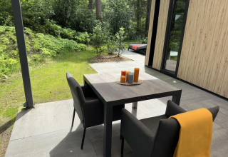 Terrasse mit Tisch, Sesseln und Kerzen bei der Veluwe Suite mit Sauna auf Camping Samoza in den Niederlanden.