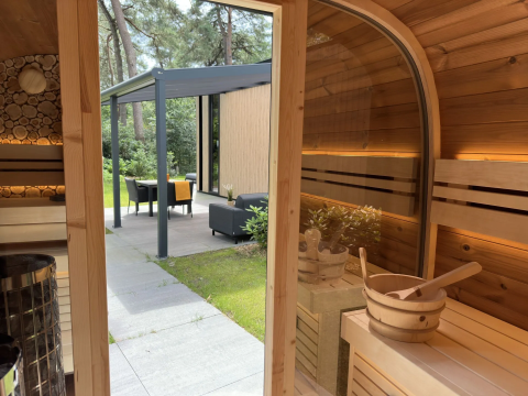 Binnenkant houten sauna met uitzicht op tuin en terras bij Veluwe Suite met sauna, Camping Samoza, Nederland.