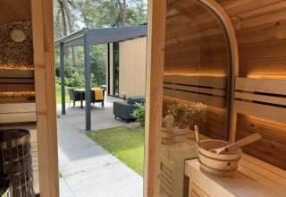 Binnenkant houten sauna met uitzicht op tuin en terras bij Veluwe Suite met sauna, Camping Samoza, Nederland.