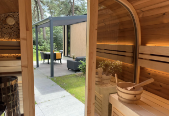 Interior de sauna de madera con vista a terraza en Veluwe Suite met sauna, Camping Samoza, Países Bajos.