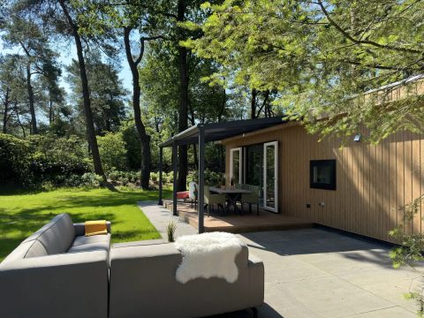 Buiten terras met zitplaatsen bij Veluwe Villa lodge op Camping Samoza, Nederland, midden in het bos.