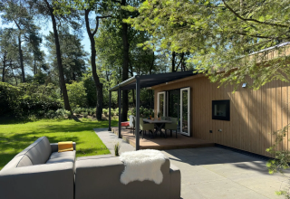 Buiten terras met zitplaatsen bij Veluwe Villa lodge op Camping Samoza, Nederland, midden in het bos.