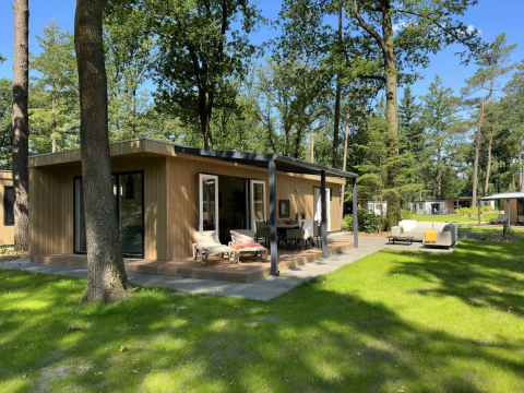 Buitenaanzicht van de Veluwe Villa lodge op Camping Samoza in Nederland, omringd door bomen en natuur.