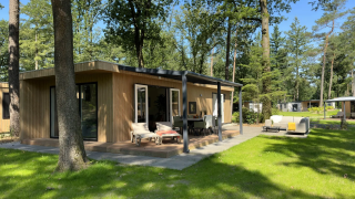 Outdoor view of the Veluwe Villa lodge at Camping Samoza in the Netherlands, surrounded by trees and nature.