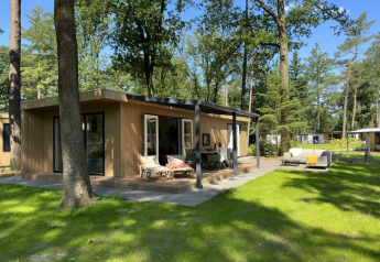 Buitenaanzicht van de Veluwe Villa lodge op Camping Samoza in Nederland, omringd door bomen en natuur.