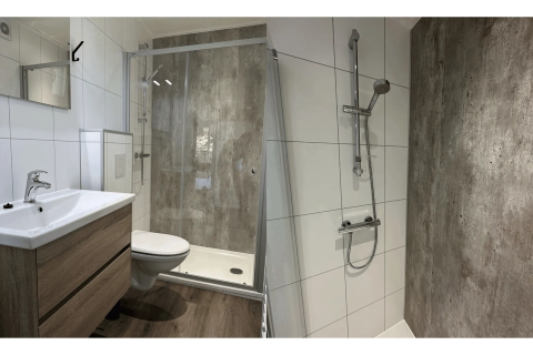 Moderne badkamer met glazen douche, houten kast en witte tegels in Veluwe Villa op Camping Samoza.