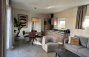 Moderne woonkamer en keuken in Zonneweelde Lodge Deluxe op Camping Zonneweelde, Nederland, met stijlvolle inrichting.