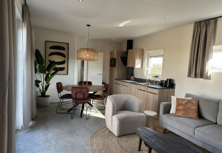 Sala de estar moderna y cocina en Zonneweelde Lodge Deluxe en Camping Zonneweelde, Países Bajos, con decoración elegante.