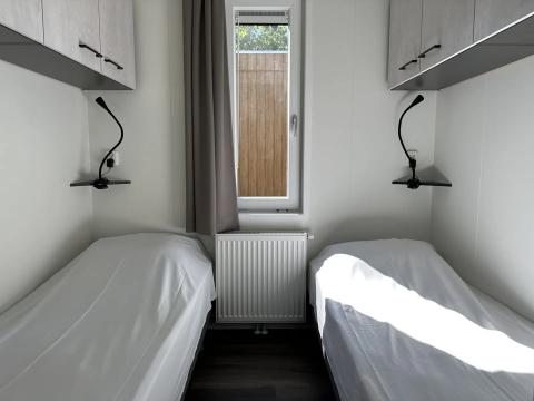 Twee eenpersoonsbedden met witte lakens in een lichte kamer van Veluwe Villa, Camping Samoza, Nederland.