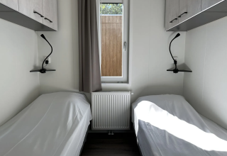 Twee eenpersoonsbedden met witte lakens in een lichte kamer van Veluwe Villa, Camping Samoza, Nederland.