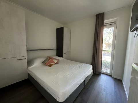 Moderne slaapkamer in Veluwe Villa bij Camping Samoza, Nederland, met tweepersoonsbed, kasten en tuinzicht.