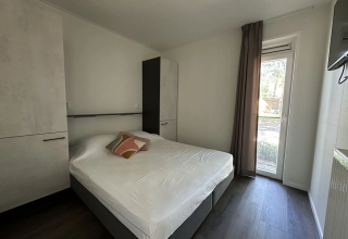 Moderne slaapkamer in Veluwe Villa bij Camping Samoza, Nederland, met tweepersoonsbed, kasten en tuinzicht.