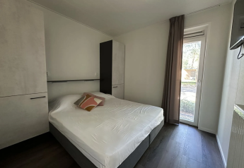 Moderne slaapkamer in Veluwe Villa bij Camping Samoza, Nederland, met tweepersoonsbed, kasten en tuinzicht.