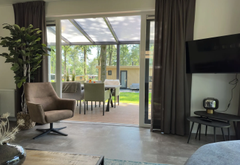 Living room at Veluwe Villa in Camping Samoza, modern interior, view of terrace and garden in Netherlands.