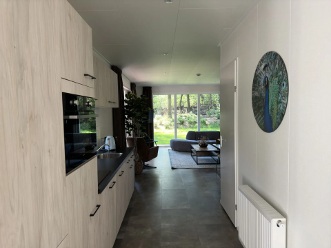 Licht interieur van Veluwe Villa Lodge op Camping Samoza in Nederland met uitzicht op de groene tuin.
