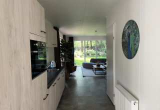 Licht keuken en leefruimte van Veluwe Villa Lodge op Camping Samoza in Nederland met tuinzicht.