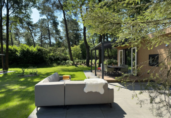 Buitenhoek met loungebank bij Veluwe Villa op Camping Samoza in Nederland, omgeven door bosrijk groen.
