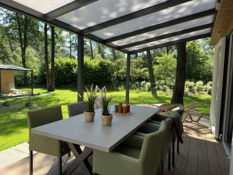 Overdekt terras bij Veluwe Villa, Camping Samoza, Nederland, met eettafel, stoelen en uitzicht op groen.