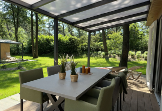 Overdekt terras bij Veluwe Villa, Camping Samoza, Nederland, met eettafel, stoelen en uitzicht op groen.