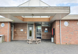 Entrance to a modern glamping accommodation with circular windows and a wooden bench in front.