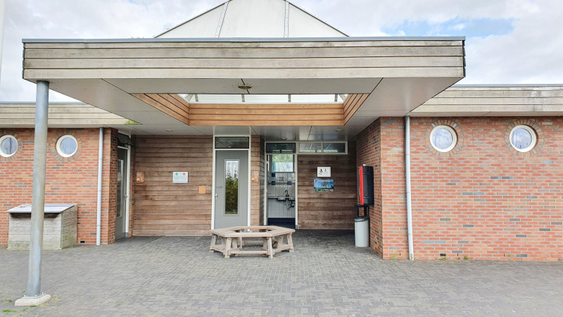 Entrance to a modern glamping accommodation with circular windows and a wooden bench in front.
