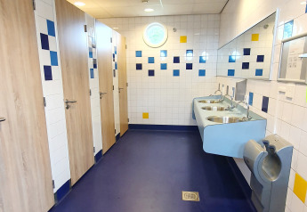 Bagno pubblico moderno a Marina Parcs Almere nei Paesi Bassi, con pavimento blu e lavandini.