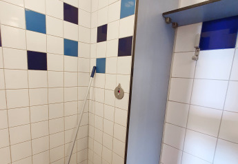 Shower area with blue and white tiles and a mop in the Water bubbles tiny house at Marina Parcs Almere.