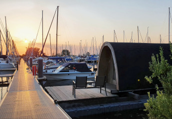 Sunset with yachts and a waterfront tiny house at Water Bubbles, Marina Parcs Almere, Netherlands.