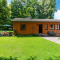 Photo d’un chalet en bois à Les Bouleaux, entouré de pelouse verte, d’arbres et de mobilier de jardin.
