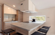 Moderne compacte keuken met houtelementen en groot raam in Chalets & Glamping Nassfeld 1, Oostenrijk.