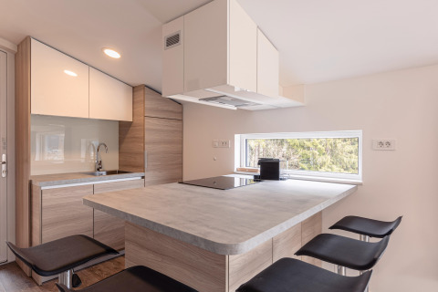 Cucina moderna e compatta con dettagli in legno e ampia finestra in Chalets & Glamping Nassfeld 1, Austria.