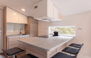 Moderne compacte keuken met houtelementen en groot raam in Chalets & Glamping Nassfeld 1, Oostenrijk.