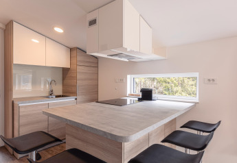Moderne compacte keuken met houtelementen en groot raam in Chalets & Glamping Nassfeld 1, Oostenrijk.