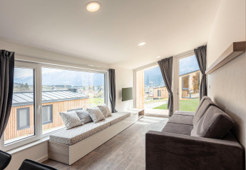 Lichte woonkamer in Chalets & Glamping Nassfeld 1, Oostenrijk, met grote ramen en uitzicht op bergen.