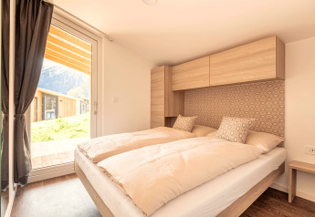 Lichte slaapkamer in Chalets & Glamping Nassfeld 1, Oostenrijk, met tweepersoonsbed en bergzicht.