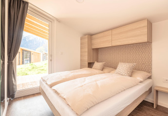 Lichte slaapkamer in Chalets & Glamping Nassfeld 1, Oostenrijk, met tweepersoonsbed en bergzicht.