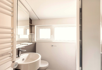 Lichte, moderne badkamer met ramen, wastafel, spiegel en douche in Chalets & Glamping Nassfeld 1, Oostenrijk.