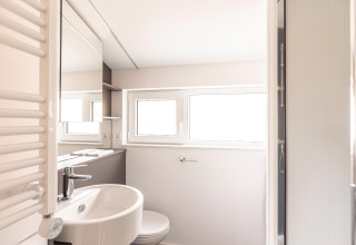 Bagno moderno e luminoso con finestre, lavandino, specchio e doccia presso Chalets & Glamping Nassfeld 1, Austria.
