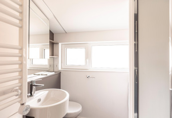 Lichte, moderne badkamer met ramen, wastafel, spiegel en douche in Chalets & Glamping Nassfeld 1, Oostenrijk.