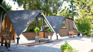 Vista esterna dello chalet Mise Au Vert con tetti triangolari, verde, alberi e cortile ghiaioso.