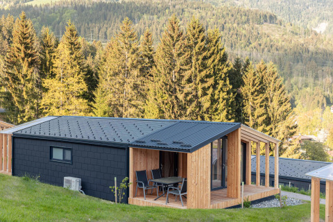 Chalet moderno con terrazza in legno e vista sulle montagne, immerso nel verde in Austria.